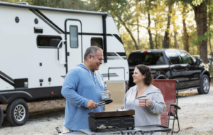 Middle-aged couple cooking outside their RV trailer.